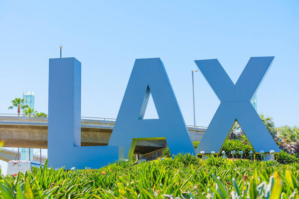 Лос-Анджелес, Калифорния - 8 апреля 2024 года: Знаменитая вывеска LAX в международном аэропорту Лос-Анджелеса, расположенная посреди пышной зелени, под безоблачным синим небом, олицетворяющим дух глобального путешествия.