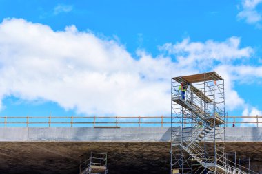 Açık mavi gökyüzü arkaplanı olan inşaat alanındaki çelik iskeleler gelişimi ve mimariyi simgeliyor..
