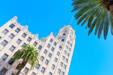 Los Angeles, Kaliforniya - 10 Nisan 2024: Hollywood 'daki First National Bank' ın tarihi binası bereketli palmiye ağaçları ile çerçevelenmiş ve açık mavi gökyüzüne karşı kurulmuştur