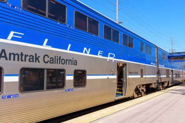 Los Angeles, California - 16 Nisan 2024: Amtrak California Surfliner treni, açık bir istasyon peronunda, güneşli bir günde açık mavi gökyüzü ile yakalandı..