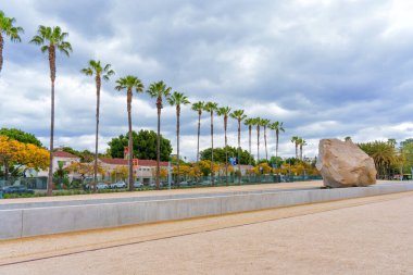Los Angeles, Kaliforniya - 4 Nisan 2024: LACMA 'da palmiye ağaçları ve bulutlu gökyüzüne karşı Iconic Levitated Mass kurulumu.