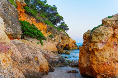 Sakin dalgalar kıyı boyunca kayalık oluşumlara çarpıyor.