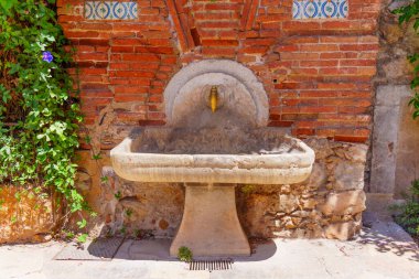 Yeşillik ve Tuğla Duvarlarla çevrili Tarihi Taş Su Çeşmesi