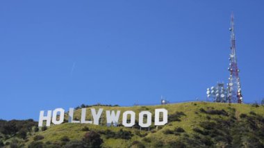 Los Angeles, California - 11 Nisan 2024: Yeşil bir tepede mavi gökyüzüne kurulmuş ikonik Hollywood tabelasının yakın görüntüsü