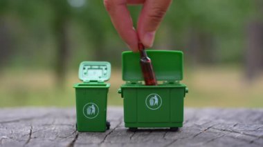 Bir el, yiyecek artıkları, cam, plastik ve kağıt gibi farklı atık türlerini ormanın içinde minyatür çöp kutularına yerleştirerek kuralları görmezden gelir..