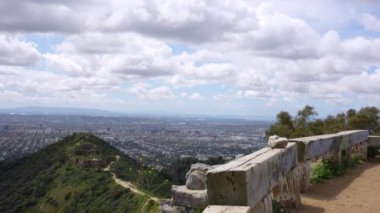 Runyon Canyon, Los Angeles 'ta ahşap çitli toprak bir patika manzarası var. Şehir manzarasına doğru gidiyor..