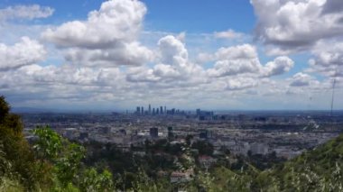 Los Angeles 'a bakan yeşil bir tepeden çarpıcı bir manzara. Şehir dramatik ve atmosferik bulutların altında yayılıyor..