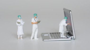 Bir grup doktor büyük bir dizüstü bilgisayarı inceliyor. Cihaz geliştirme kavramına odaklanın ve yenilikçi teknoloji çözümlerini test edin.