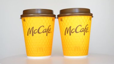 Kyiv, Ukrayna - 24 Eylül 2024: McCafe turuncu fincanlarını bir masadan tek tek alan, canlı renklerini ve markalarını gösteren bir el..