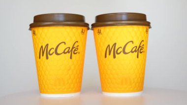 Kyiv, Ukrayna - 24 Eylül 2024: İki McCafe turuncu bardağı beyaz arka planda yan yana yerleştiriliyor, canlı renklerini ve markalarını sergiliyorlar.