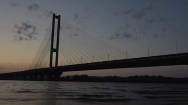 Dinyeper nehri boyunca uzanan kablo destekli bir köprünün günbatımı manzarası.