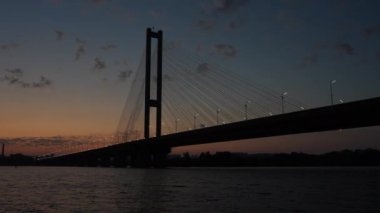 Güney Köprüsü 'nün alacakaranlıktaki Dnipro Nehri üzerindeki alçak açılı su yüzeyi manzarası sokak lambalarıyla parıldıyor..