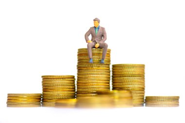 Yığılmış Altın Paraların Üzerinde oturan Minyatür İşadamı