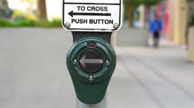 Los Angeles 'taki trafik ışıklarında yaya geçidi tuşuna basan bir elin yakın çekimi..