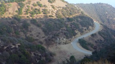 Runyon Canyon Parkı 'ndaki virajlı patikaların ve tepelerin panoramik manzarası. Los Angeles şehrine tepeden bakan insanlar yürüyor..