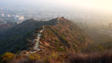 180 derecelik sıvı panorama, Los Angeles şehrinin arka planında, altın saatinde bir yürüyüş patikası ve tepeler gösteriyor..