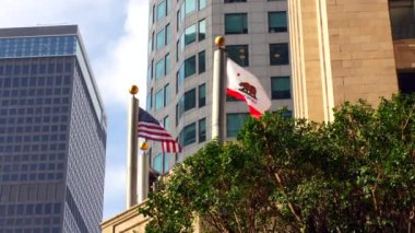 Los Angeles, Kaliforniya - 4 Aralık 2024: Kaliforniya ve şehir merkezindeki gökdelenlerin arasında dalgalanan Amerikan bayrakları, Los Angeles 'ın şehir manzarasını ve gururunu gözler önüne seriyor.