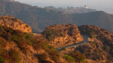 Runyon Canyon 'dan panoramik manzara yürüyüş pistleri, Griffith Gözlemevi, yamaçtaki evler, uçan kuşlar ve puslu Los Angeles silueti..