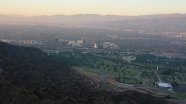 Hollywood Hills 'teki Forest Lawn Mezarlığı' nın çarpıcı hava perspektifi yeşil çimenler, virajlı yollar ve uzak şehir silueti sergilenmektedir..