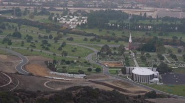 Hollywood Hills 'ten yakalanan Orman Çim Mezarlığı' nın geniş panoramik manzarası, yemyeşil çimenler, dolambaçlı yollar ve sakin anıtlarla dolu..