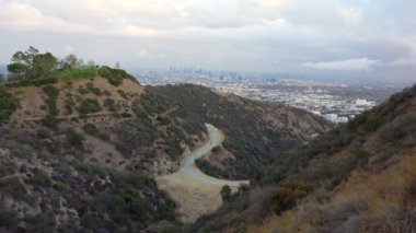 Doğanın ihtişamını ve Los Angeles ufkunu gözler önüne seren çarpıcı manzara, dolambaçlı patikalar boyunca yürüyen küçük figürler..