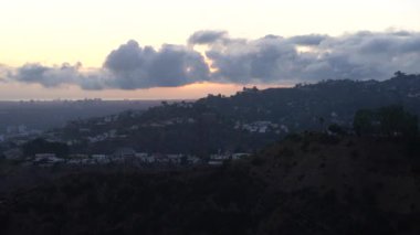 Los Angeles 'ın panoramik manzarasını gösteren alacakaranlık sahnesi. Şehir ışıkları ve Runyon Canyon' dan gelen dramatik bulutların karışımı..
