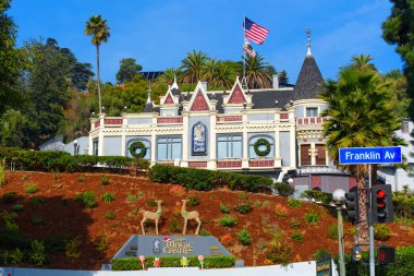 Los Angeles, Kaliforniya - 24 Aralık 2024: Los Angeles 'taki Sihirli Şato, güzel bir şekilde çelenk ve Amerikan bayrağıyla süslenmiş, açık mavi gökyüzüne karşı duruyor.