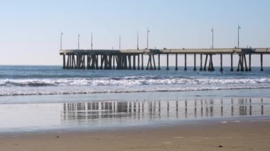 Los Angeles, Kaliforniya - 18 Aralık 2024: Venedik Balıkçılık İskelesi 'nin panoramik manzarası sakin okyanus dalgaları ve kumlu bir plaja karşı kurulmuş, rahatlatıcı bir sahil atmosferini vurguluyor..