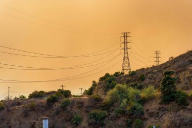 Los Angeles, California - January 8, 2025: Power Lines Silhouetted Against Smoky Orange Sky clipart