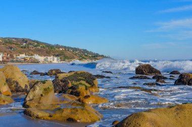 Malibu sahilinde dalgalar ve kayalar Panorama 'da evler