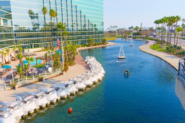 Long Beach, California - 11 Ocak 2025: Long Beach, Kaliforniya 'daki Hyatt Regency Hotel' in çarpıcı manzarası modern mimarisi ve kuğu şekilli teknelerle huzurlu deniz manzarası sergilenmektedir..