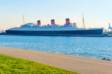 Long Beach, California - 11 Ocak 2025: Tarihi bir okyanus gemisi ve müzesi olan İkonik Kraliçe Mary, açık bir günbatımında Long Beach 'in limanında görkemli bir şekilde yüzer ve deniz zarafetinin canlılığını ve tarihini yakalar..