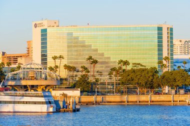 Long Beach, California - 11 Ocak 2025 Long Beach, Kaliforniya 'daki Hyatt Regency binasının yansıtıcı cam cephesi, liman manzarası, palmiye ağaçları ve günbatımı ambiyansı geniş açılı bir açıyla çekildi..