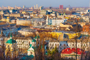 Kyiv, Ukrayna - 9 Mart 2025: Kontraktova Meydanı yakınlarındaki Podil ilçesinin geniş açılı görüntüsü, renkli binalar, dönme dolap ve Kyiv 'in ufuk çizgisini altın saat boyunca açık hava altında yakalıyor.
