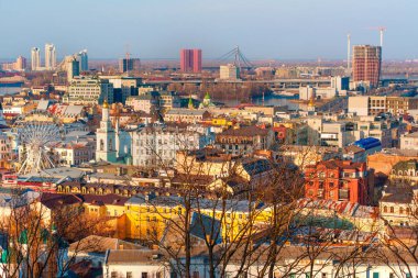 Kyiv, Ukrayna - 9 Mart 2025: Kontraktova Meydanı yakınlarındaki Podil ilçesinin canlı hava görüntüleri, modern binalar, tarihi mimari ve açık gökyüzü altında bir dönme dolap yer alıyor.