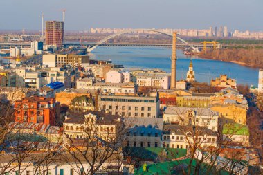 Kyiv, Ukrayna - 9 Mart 2025: Kontraktova Meydanı yakınlarındaki Podil ilçesinin panoramik manzarası, binalar ve Dinyeper Nehri, açık gökyüzü ve parlak renklerle sabah erken saatlerde.