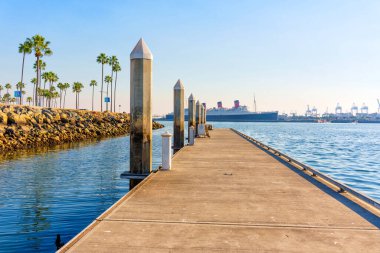 Long Beach, California - 11 Ocak 2025: Iconic Queen Mary gemisi Long Beach, California 'da demirlemiş, palmiye ağaçları manzaralı rıhtımı kaplamıştı..