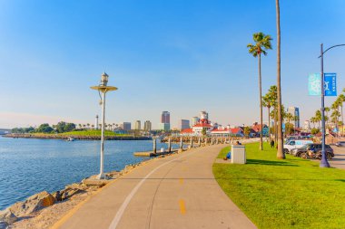 Long Beach, California - 11 Ocak 2025: Long Beach, Kaliforniya 'daki Parkers Deniz Feneri Deniz Ürünleri Restoranı' nın sahnesi, palmiye ağaçları, su yansımaları ve parlak mavi gökyüzü altında ufuk çizgisi.