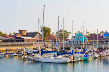 Long Beach, California - 11 Ocak 2025: Gökkuşağı Limanı 'na demirlemiş renkli yelkenliler, sahil kenarındaki restoranlar ve Shoreline Village' ın dükkanları tarafından sıcak akşam ışığında ele geçirildi..