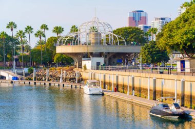 Long Beach, California - 11 Ocak 2025: Canlı Long Beach sahnesinde palmiye ağaçları, sahil boyunda tekneler ve geniş açılı mavi bir gökyüzü bulunan bir kongre merkezi yürüyüş asansörü yer alıyor..