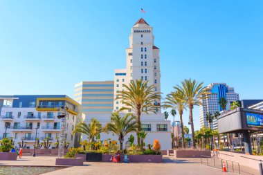 Long Beach, California - 10 Ocak 2025 Long Beach Fairmont Breakers Oteli palmiye ağaçları, modern binalar ve berrak mavi gökyüzü ile canlı bir şehir atmosferini resmediyordu..