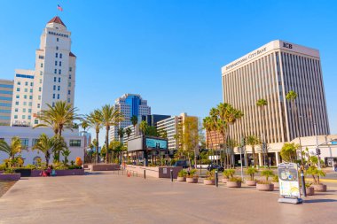 Long Beach, California - 10 Ocak 2025: Long Beach, Kaliforniya 'da Fairmont Breakers ve International City Bank' ı görüntüleyen manzara güneşli bir gün, palmiye ağaçları ve parlak mavi gökyüzü ile canlı şehir mimarisi.
