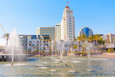 Long Beach, California - 10 Ocak 2025: Long Beach 'teki Fairmont Breakers Hotel' in canlı bir çeşme görüntüsü, açık mavi gökyüzü ve kıyı zeminine karşı modern mimari.