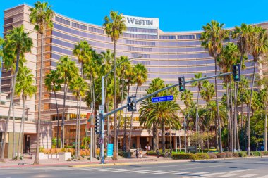 Long Beach, California - 10 Ocak 2025: Long Beach, Kaliforniya 'daki modern Westin Hotel' in geniş açılı görüntüsü, palmiye ağaçları, güneşli hava ve Long Beach Bulvarı 'ndaki yayalar için ideal..