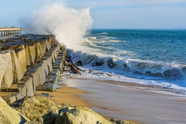 Dinamik dalgalar San Pedro 'daki Cabrillo Sahili' nin kayalık sahil şeridine çarpıyor. Parlak mavi gökyüzü ve sakin sular altında doğal kıyı güzelliğini sergiliyor..