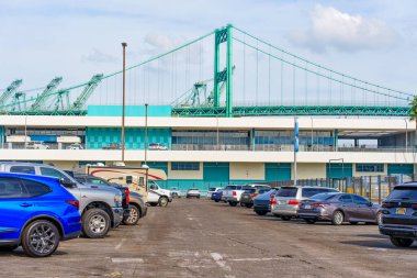 Los Angeles, Kaliforniya - 25 Aralık 2024: Geniş açılı görüntü, Los Angeles Limanı 'na yakın park etmiş araçları yakalıyor, konteynır terminali ve ikonik köprü yapısını vurguluyor..