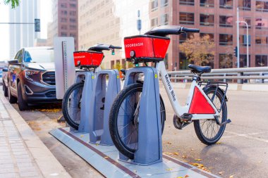 Los Angeles, Kaliforniya - 3 Aralık 2024: Los Angeles şehir merkezindeki kiralık bir istasyona kenetlenmiş, canlı bir şehir ortamında bisiklet paylaşımı sergilenen DoorDash markalı bisikletlerin yakın görüntüsü.