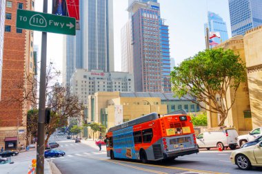 Los Angeles, Kaliforniya - 4 Aralık 2024: Canlı şehir manzarası Los Angeles Merkez Kütüphanesi 'nden geçen bir otobüsü yakalıyor, şehir mimarisini ve açık gökyüzünü gösteriyor.