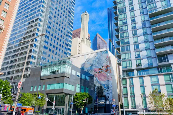 Los Angeles, Kaliforniya - 3 Aralık 2024: Parlak mavi gökyüzü altında modern mimari, canlı duvar resimleri ve dinamik kentsel yaşam içeren hareketli Los Angeles kavşağı.
