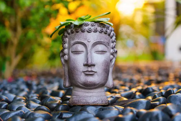 Los Angeles, Kaliforniya - 7 Aralık 2024: Serene Buddha heykeli sulu süslemelerle süslenmiş, pürüzsüz çakıl taşlarından oluşan arka planda sergilenen sakin açık hava aydınlatması.